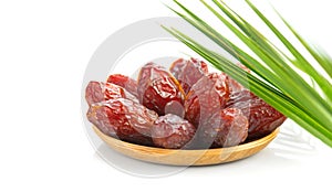 Dates fruit. Date fruits in wooden bowl with palm tree leaf isolated on white background. Organic Medjool dates