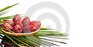 Dates fruit. Date fruits in wooden bowl with palm tree leaf isolated on white background. Organic Medjool dates