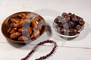 Dates fruit and rosary on white wooden table