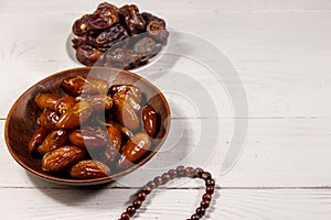 Dates fruit and rosary on white wooden table