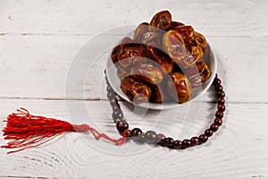 Dates fruit and rosary on white wooden table