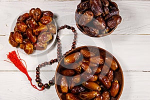 Dates fruit and rosary on white wooden table. Top view