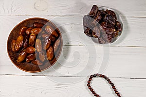 Dates fruit and rosary on white wooden table. Top view