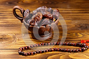 Dates fruit and rosary on wooden table