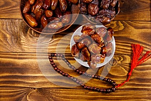 Dates fruit and rosary on wooden table. Top view