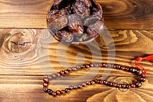 Dates fruit and rosary on wooden table. Top view