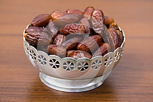 Dates fruit on a silver bowl on wooden table