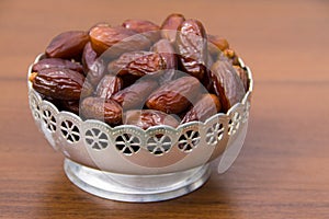 Dates fruit on a silver bowl on wooden table