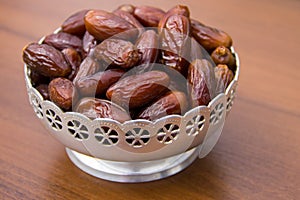 Dates fruit on a silver bowl on wooden table