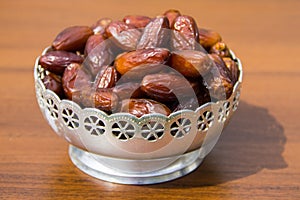 Dates fruit on a silver bowl on wooden table