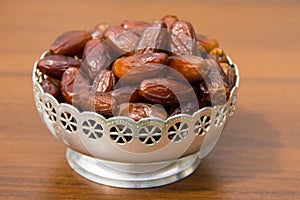 Dates fruit on a silver bowl on wooden table