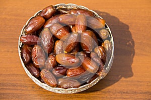 Dates fruit on a silver bowl on wooden table