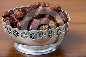 Dates fruit on a silver bowl on wooden table