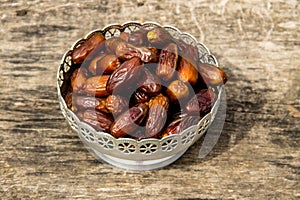 Dates fruit on silver bowl on wooden table. The Muslim feast of the holy month of Ramadan Kareem