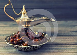 Dates and golden arabian lamp on wooden background. Oriental foo