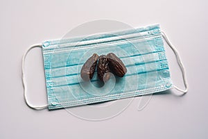 Dates or kurma with medical mask on white background