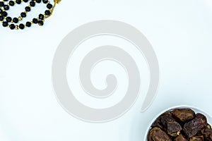 Dates in plastic container with prayer beads over white background