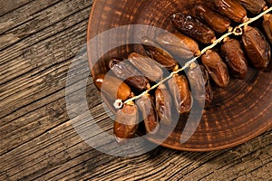 Dates tropical fruit branch in plate on old wooden background