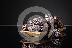 Dates in wooden dish on a black background