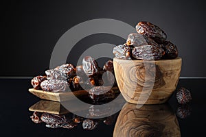 Dates in wooden dish on a black background