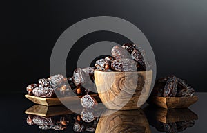 Dates in wooden dish on a black background