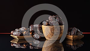 Dates in wooden dish on a black background