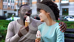 Dating couple eating ice-cream, sitting on city bench, having fun together, love