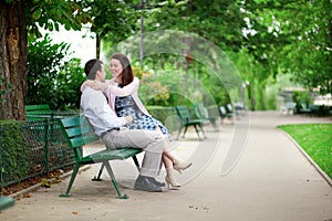 Dating couple hugging on a bench in a Parisian park