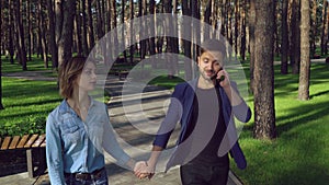 Dating pair in the park. Caucasian girl wearing in casual dress denim shirt guy dressed in blue stylish jacket.