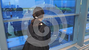 Daughter with a backpack airplane flights airport concept. girl teenager with a smartphone looks out the window at the