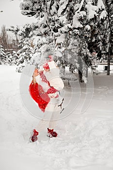 Daughter blows snow from a spruce branch onto her mother. mom and daughter blonde on a background of snow and large Christmas