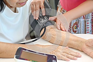 Daughter checking mother`s blood pressure hypertension photo