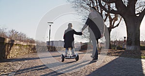 Daughter child girl learning segway riding with dad teaching in city.Modern future transport technology.Active safety