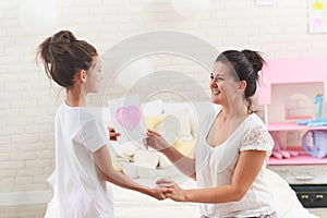 Daughter congratulates her mother. A girl gives a card with a heart to her mom