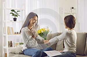 Daughter congratulates her mother on Mother& x27;s Day by giving her flowers and handmade card.