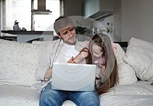 Daughter disturbing stressed father in living room. Working from home during quarantine.