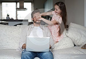 Daughter disturbing stressed father in living room. Working from home during quarantine.