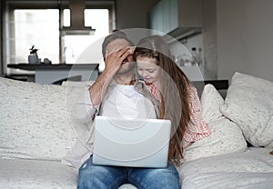 Daughter disturbing stressed father in living room. Working from home during quarantine.