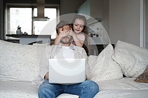 Daughter disturbing stressed father in living room. Working from home during quarantine.