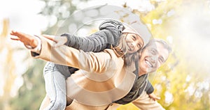 Daughter and father have fun playing airplanes outdoors on a sunny autumn day