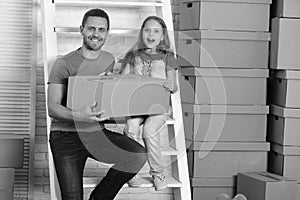 Daughter and father hold boxes and unpack or pack. Girl and man with smiling and surprised faces with ladder