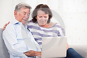 Daughter and father laughing while using laptop