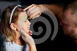 Daughter and father paint a face, having fun, leisure together at home