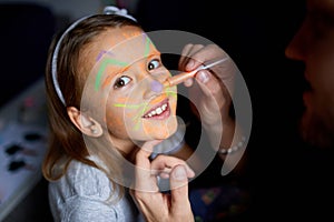 Daughter and father paint a face, having fun, leisure together at home