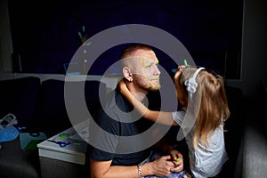 Daughter and father paint a face, having fun, leisure together at home