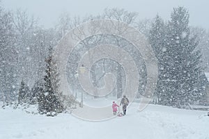 Daughter with father on a sled in a snowy park in snowy weather.