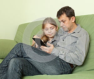 Daughter and father using e-book