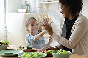 Daughter give high five to african mom cooking together indoor