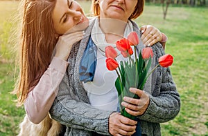 Daughter gives her mother tulips. Mother`s day present