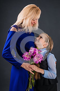 Daughter gives mother flowers and sincerely congratulate her on the occasion